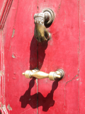 Türgriff und Türklopfer (Hand) aus Kupfer auf roter Tür